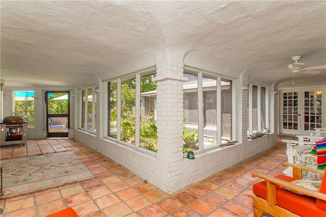 unfurnished sunroom with a textured ceiling, french doors, and decorative columns