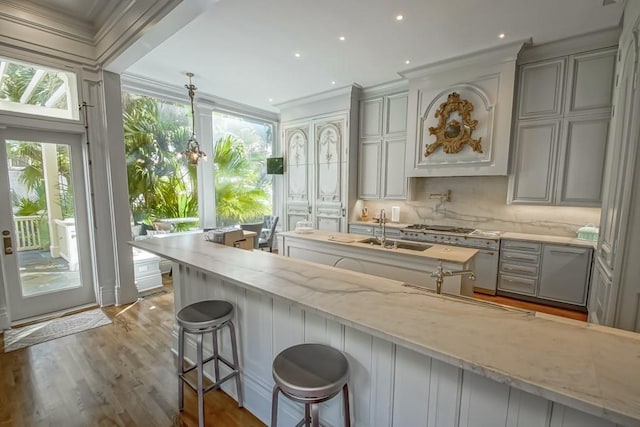 1711 Palmer Ave, New Orleans, LA 70118 - kitchen featuring ornamental molding, a sink, light stone countertops, a kitchen bar, and wood finished floors