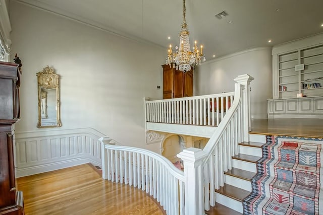 1711 Palmer Ave, New Orleans, LA 70118 - staircase featuring a chandelier, wood finished floors, ornamental molding, a wainscoted wall, and recessed lighting