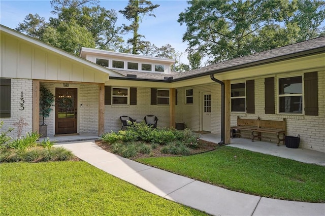exterior space featuring brick siding, board and batten siding, and a lawn