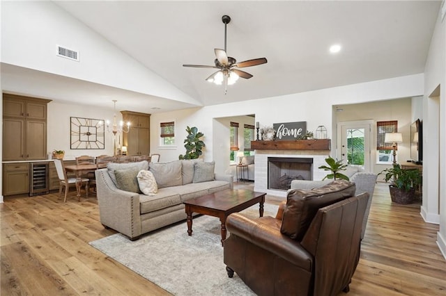 living room with light wood finished floors, wine cooler, visible vents, vaulted ceiling, and ceiling fan with notable chandelier