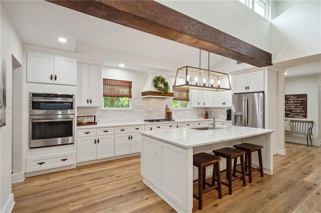 kitchen featuring stainless steel appliances, premium range hood, backsplash, and a sink