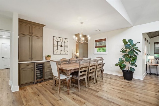 dining space featuring baseboards, a notable chandelier, light wood-style flooring, and wine cooler