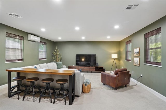 living room featuring baseboards, visible vents, carpet floors, and a wall mounted AC