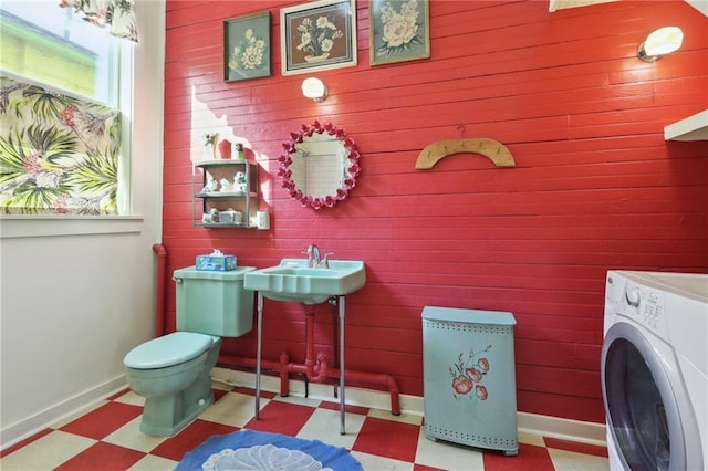 bathroom featuring tile patterned floors, wood walls, washer / dryer, toilet, and baseboards