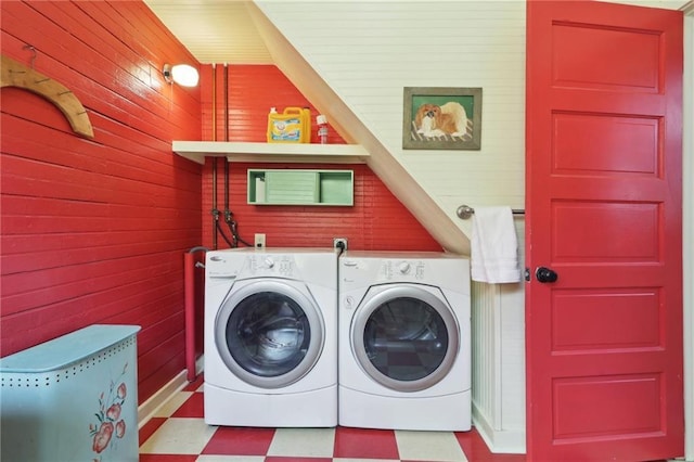 laundry area featuring washer and clothes dryer, tile patterned floors, wooden walls, and laundry area