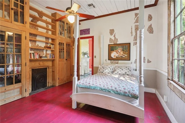 bedroom featuring a fireplace with flush hearth, crown molding, visible vents, a wainscoted wall, and wood finished floors