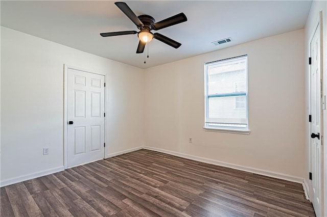 empty room featuring dark wood finished floors, a ceiling fan, and baseboards