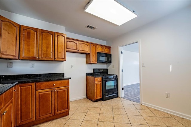kitchen with black appliances, brown cabinets, baseboards, light tile patterned flooring, and dark stone counters