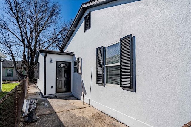 entrance to property with stucco siding and fence