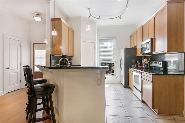 kitchen with a peninsula, a breakfast bar, range with electric stovetop, stainless steel microwave, and tasteful backsplash