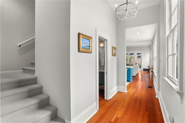 5934 Chestnut St, New Orleans, LA 70118 - hallway featuring an inviting chandelier, stairway, wood finished floors, and baseboards