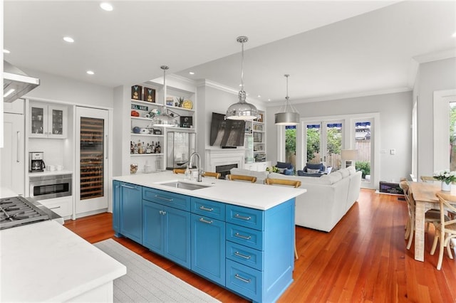 5934 Chestnut St, New Orleans, LA 70118 - kitchen with a sink, a fireplace, blue cabinetry, light countertops, and ornamental molding