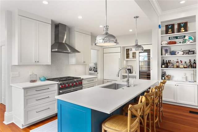 5934 Chestnut St, New Orleans, LA 70118 - kitchen with wood finished floors, high end appliances, ornamental molding, a sink, and wall chimney exhaust hood