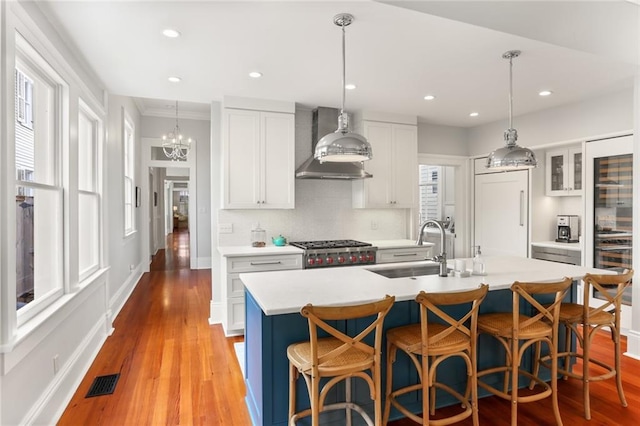 5934 Chestnut St, New Orleans, LA 70118 - kitchen with a breakfast bar area, a sink, visible vents, light countertops, and wall chimney exhaust hood