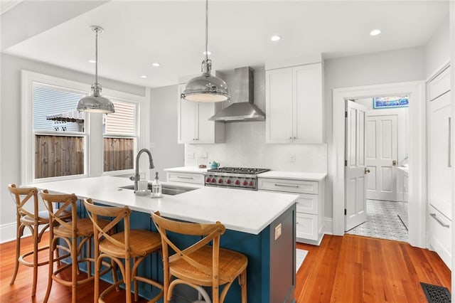 5934 Chestnut St, New Orleans, LA 70118 - kitchen with wall chimney exhaust hood, a sink, light wood-style floors, and light countertops