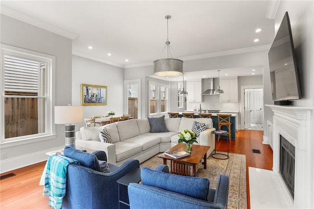 5934 Chestnut St, New Orleans, LA 70118 - living room featuring a fireplace with flush hearth, crown molding, visible vents, recessed lighting, and wood finished floors