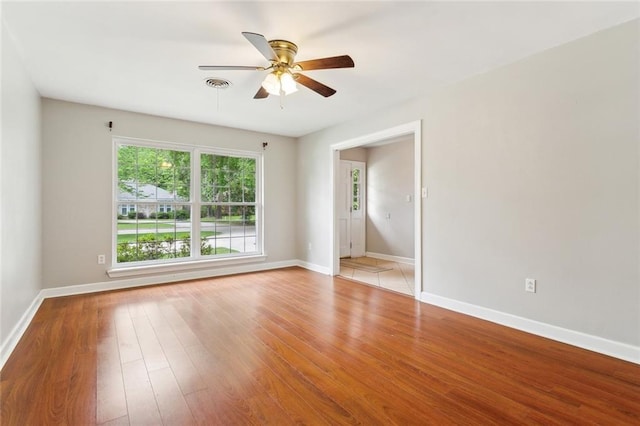 empty room with baseboards, visible vents, ceiling fan, and light wood-style flooring