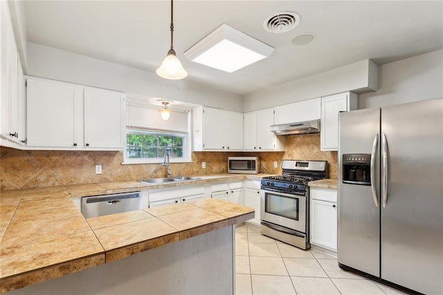 kitchen featuring a sink, stainless steel appliances, under cabinet range hood, light tile patterned floors, and visible vents
