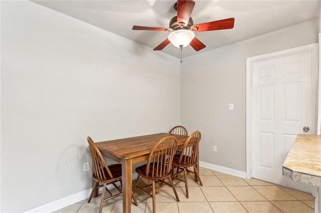 dining area with light tile patterned flooring, a ceiling fan, and baseboards