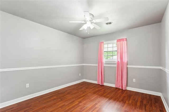 spare room featuring baseboards, visible vents, wood finished floors, and a ceiling fan