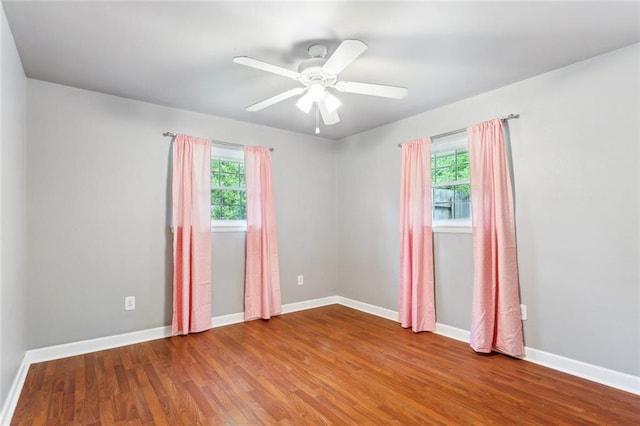 empty room featuring wood finished floors, plenty of natural light, a ceiling fan, and baseboards