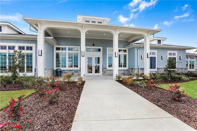 5520 Wake Reserve Rd, Slidell, LA 70461 - exterior space with covered porch, french doors, concrete driveway, stone siding, and stucco siding