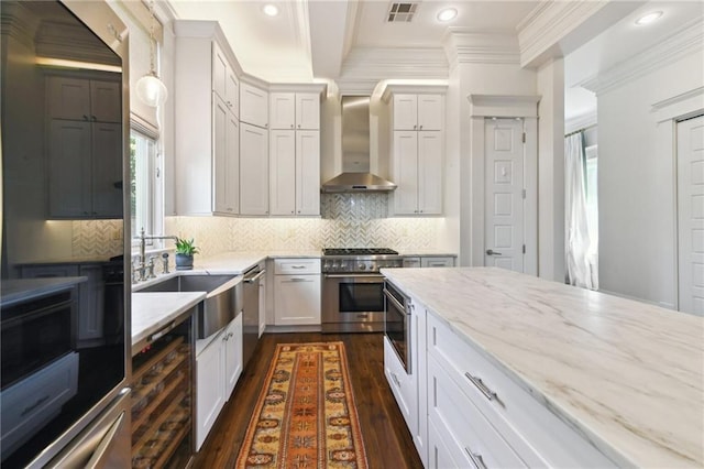 616 Cadiz St, New Orleans, LA 70115 - kitchen with stainless steel appliances, visible vents, light stone counters, wall chimney range hood, and dark wood finished floors
