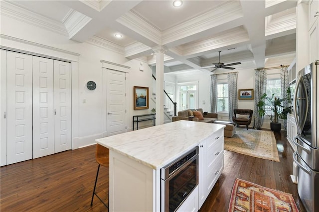 616 Cadiz St, New Orleans, LA 70115 - kitchen with dark wood-style floors, stainless steel appliances, coffered ceiling, and a kitchen breakfast bar