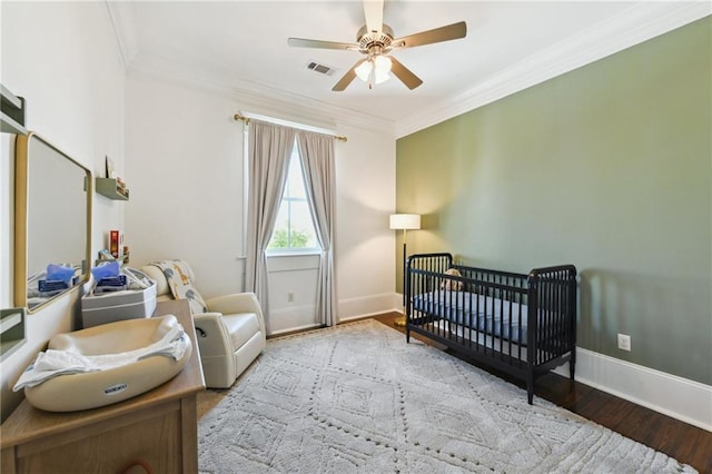 616 Cadiz St, New Orleans, LA 70115 - bedroom with wood finished floors, a nursery area, ornamental molding, baseboards, and visible vents