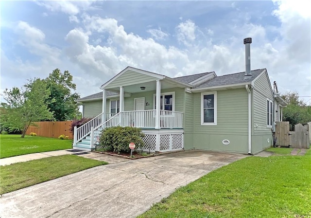 view of front of house with covered porch, fence, a front lawn, and roof with shingles