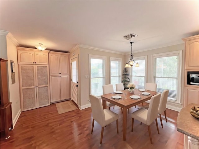 dining space featuring wood finished floors, visible vents, ornamental molding, and baseboards