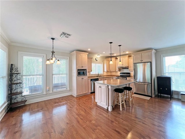 kitchen with wood finished floors, stainless steel appliances, under cabinet range hood, a sink, and visible vents