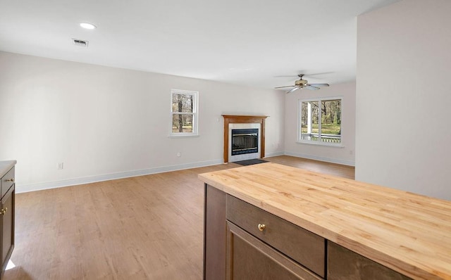 unfurnished living room with visible vents, ceiling fan, baseboards, and light wood-style floors