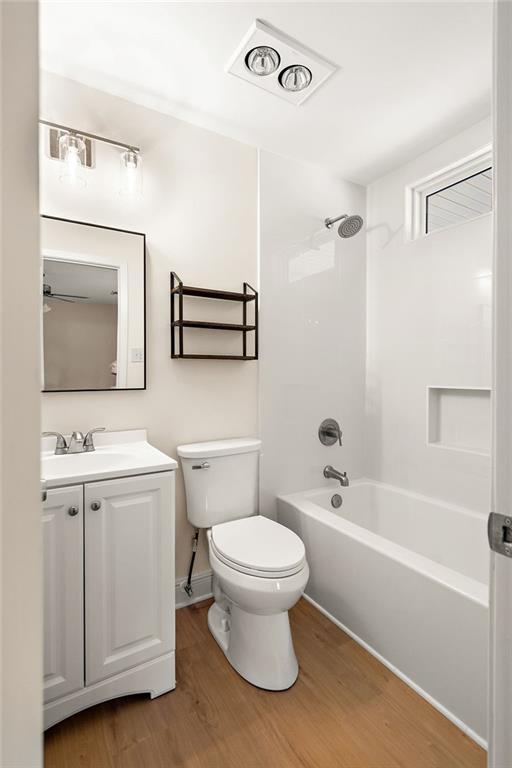 full bath featuring visible vents, toilet, shower / bathing tub combination, wood finished floors, and vanity