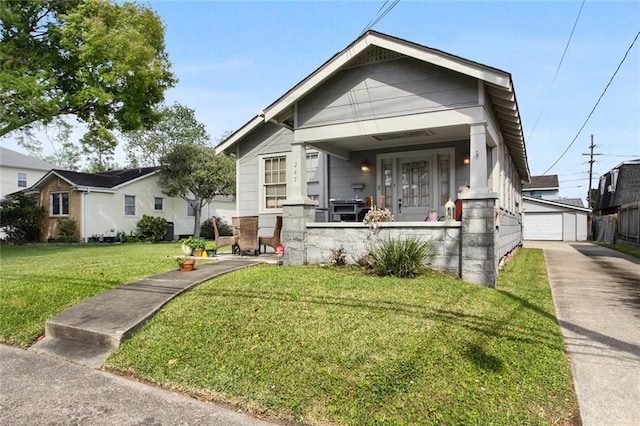 shotgun-style home featuring covered porch, an outbuilding, a front yard, and a garage