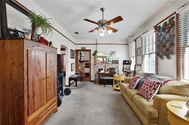 living area with arched walkways, ceiling fan, visible vents, and carpet