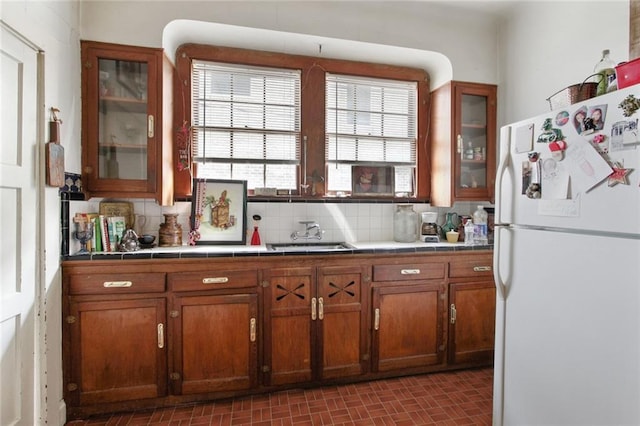 kitchen with freestanding refrigerator, a sink, tile countertops, and brown cabinets