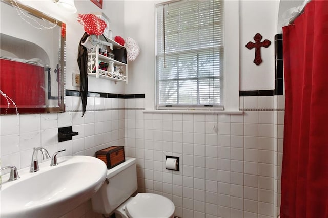 full bath with curtained shower, toilet, tile walls, a wainscoted wall, and a sink