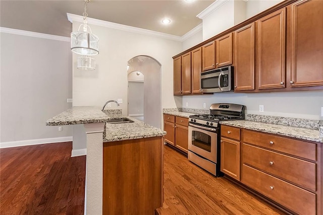 kitchen featuring a sink, dark wood-type flooring, crown molding, arched walkways, and appliances with stainless steel finishes