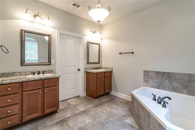 bathroom featuring a garden tub, two vanities, a sink, and visible vents