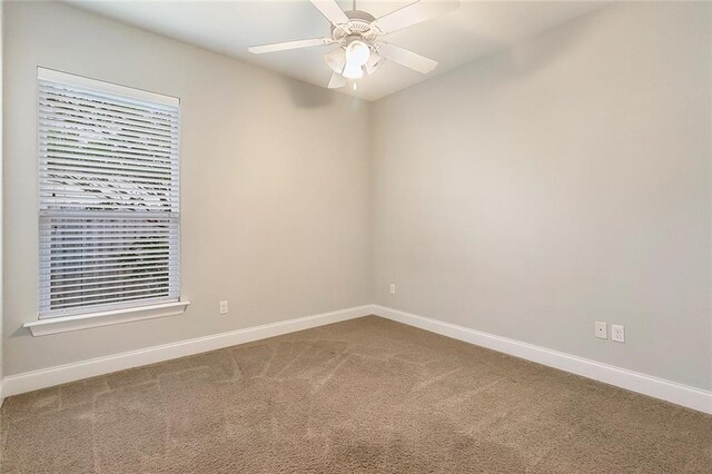 carpeted spare room featuring a ceiling fan and baseboards