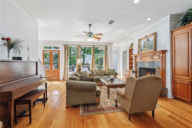 454 Rutherford Dr, Covington, LA 70433 - living room featuring a tile fireplace, ceiling fan, visible vents, light wood-style flooring, and ornamental molding