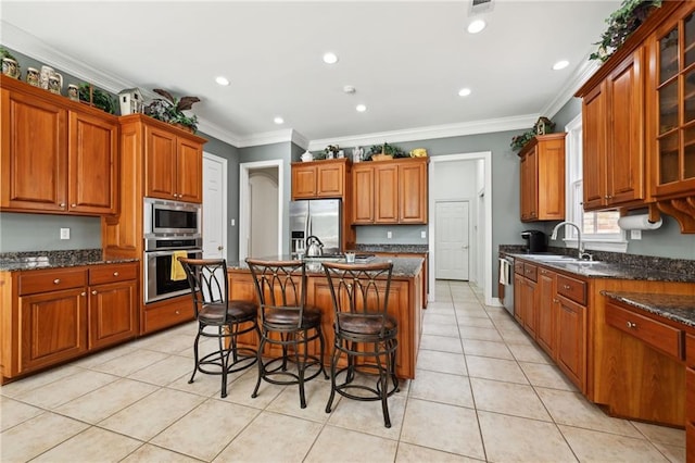 454 Rutherford Dr, Covington, LA 70433 - kitchen with a kitchen island with sink, light tile patterned floors, stainless steel appliances, and brown cabinetry