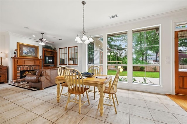 454 Rutherford Dr, Covington, LA 70433 - dining area featuring a fireplace, light tile patterned floors, visible vents, ornamental molding, and ceiling fan with notable chandelier
