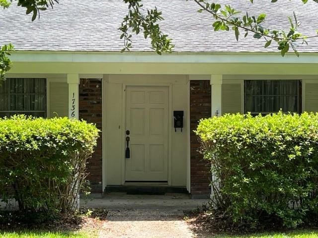 1736 11th St, Slidell, LA 70458 - doorway to property with a shingled roof, brick siding, and a porch