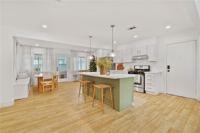 117 Diane Ave, River Ridge, LA 70123 - kitchen with gas stove, under cabinet range hood, light wood finished floors, a kitchen island, and light countertops