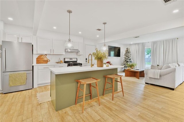 117 Diane Ave, River Ridge, LA 70123 - kitchen with appliances with stainless steel finishes, white cabinets, light wood-style floors, open floor plan, and a kitchen bar