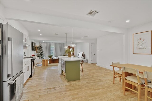 117 Diane Ave, River Ridge, LA 70123 - kitchen with appliances with stainless steel finishes, a breakfast bar, under cabinet range hood, light wood-style flooring, and light countertops