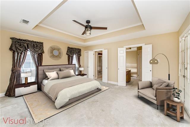 bedroom featuring a tray ceiling, light carpet, baseboards, and ceiling fan